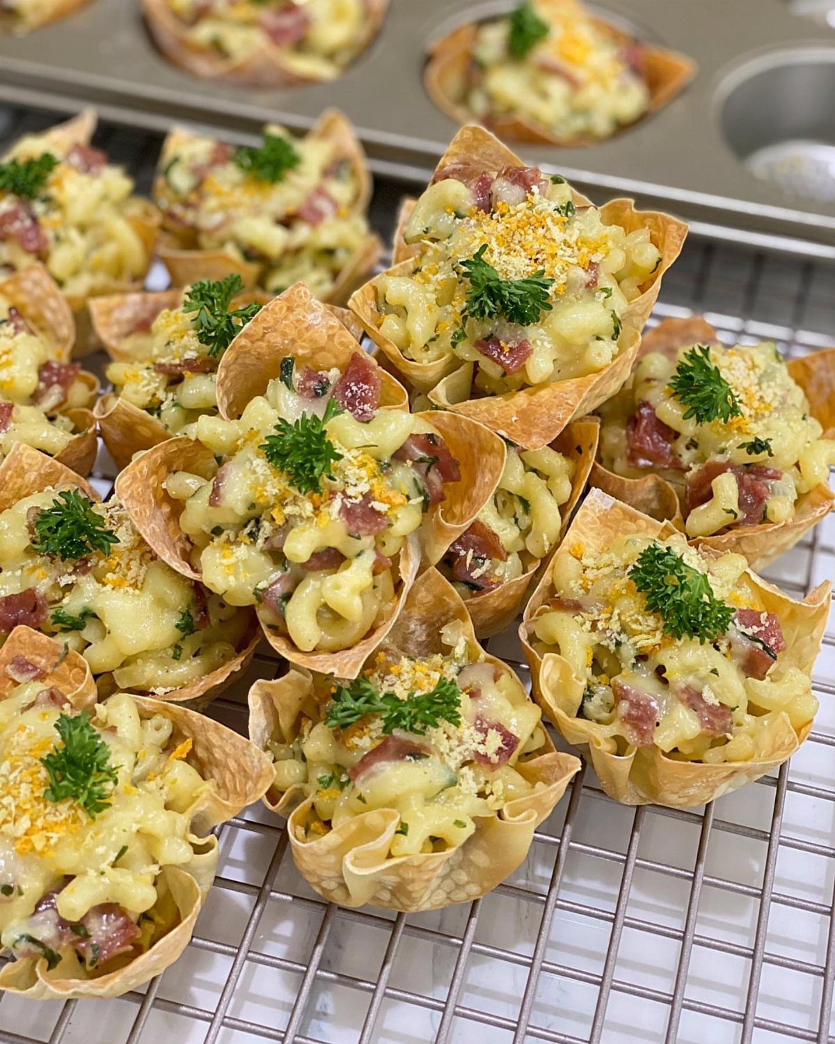 Mini macaroni and cheese bites with ham and parsley in pastry cups.