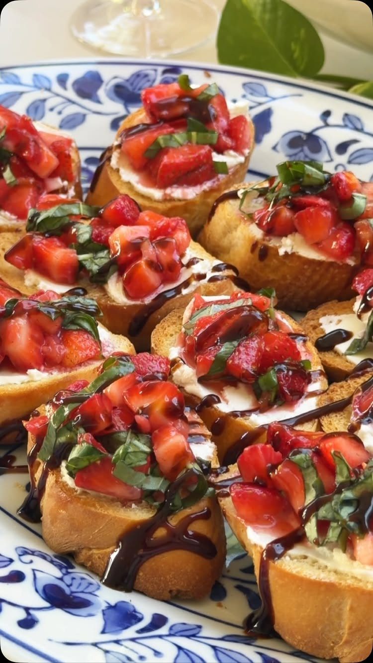 Strawberry bruschetta with creamy cheese, fresh basil, and balsamic glaze on a plate.
