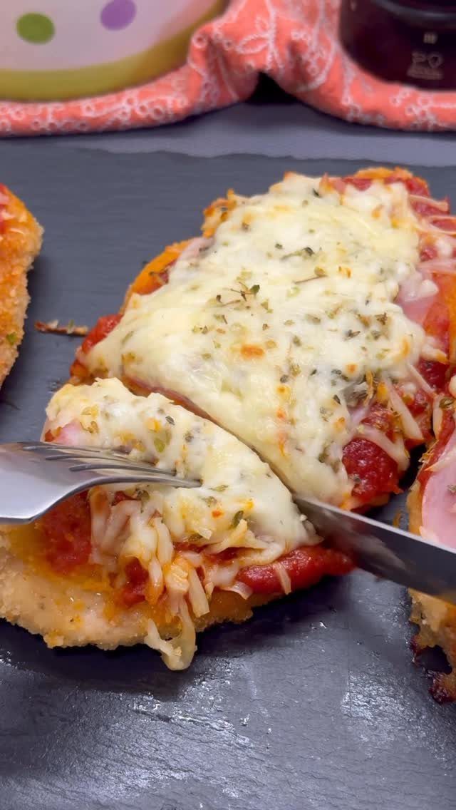 Chicken parmesan with melted cheese and tomato sauce on a dark slate platter