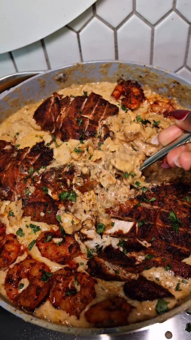 Seared steak and shrimp in a creamy sauce served in a stainless steel pan.