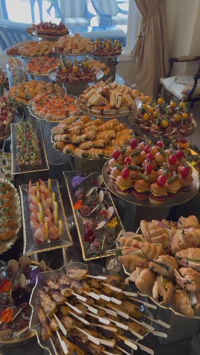 Buffet spread of gourmet appetizers, sliders, and shrimp on tiered platters for a party.