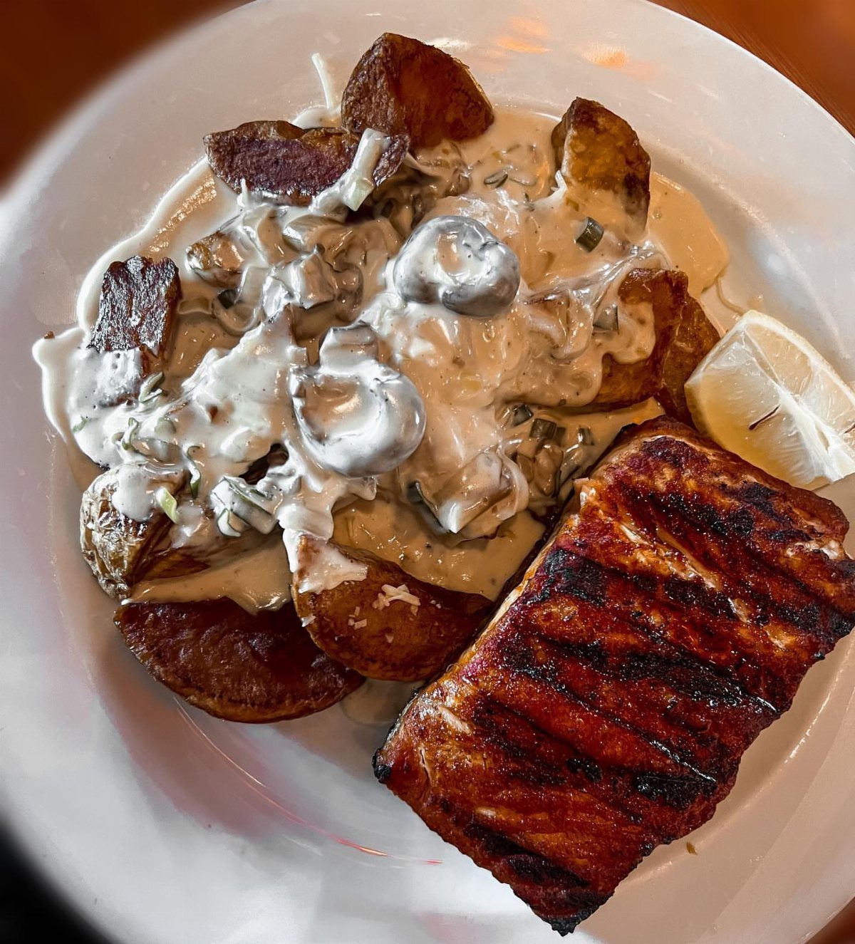 Grilled salmon fillet with roasted potato wedges and creamy mushroom sauce on a plate