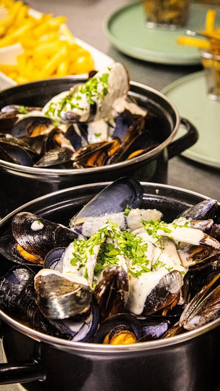 Mussels in creamy white sauce with parsley served with golden french fries.