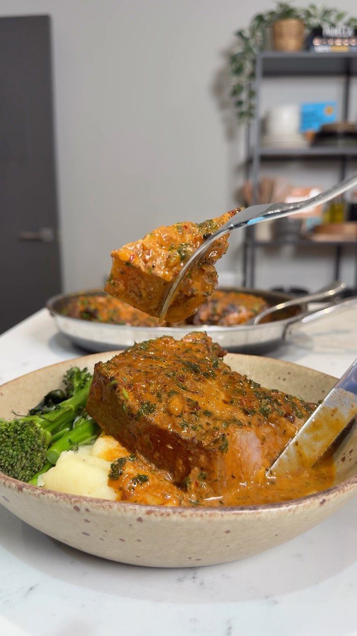 Meat with herb sauce, mashed potatoes, and broccoli served in a beige bowl.