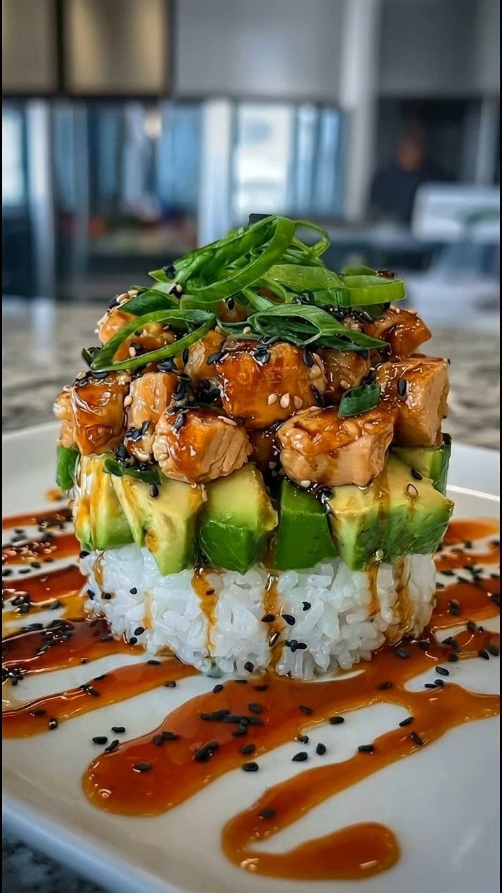 Glazed salmon bites stacked on avocado and rice with green onion garnish.