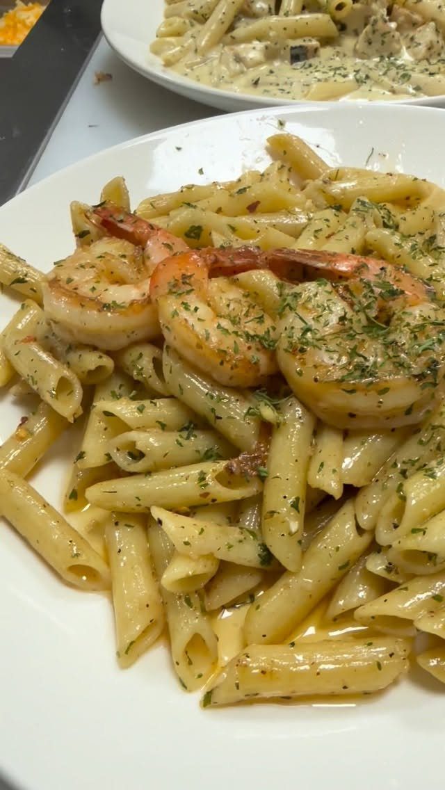 Penne pasta with garlic butter sauce and shrimp topped with fresh green herbs