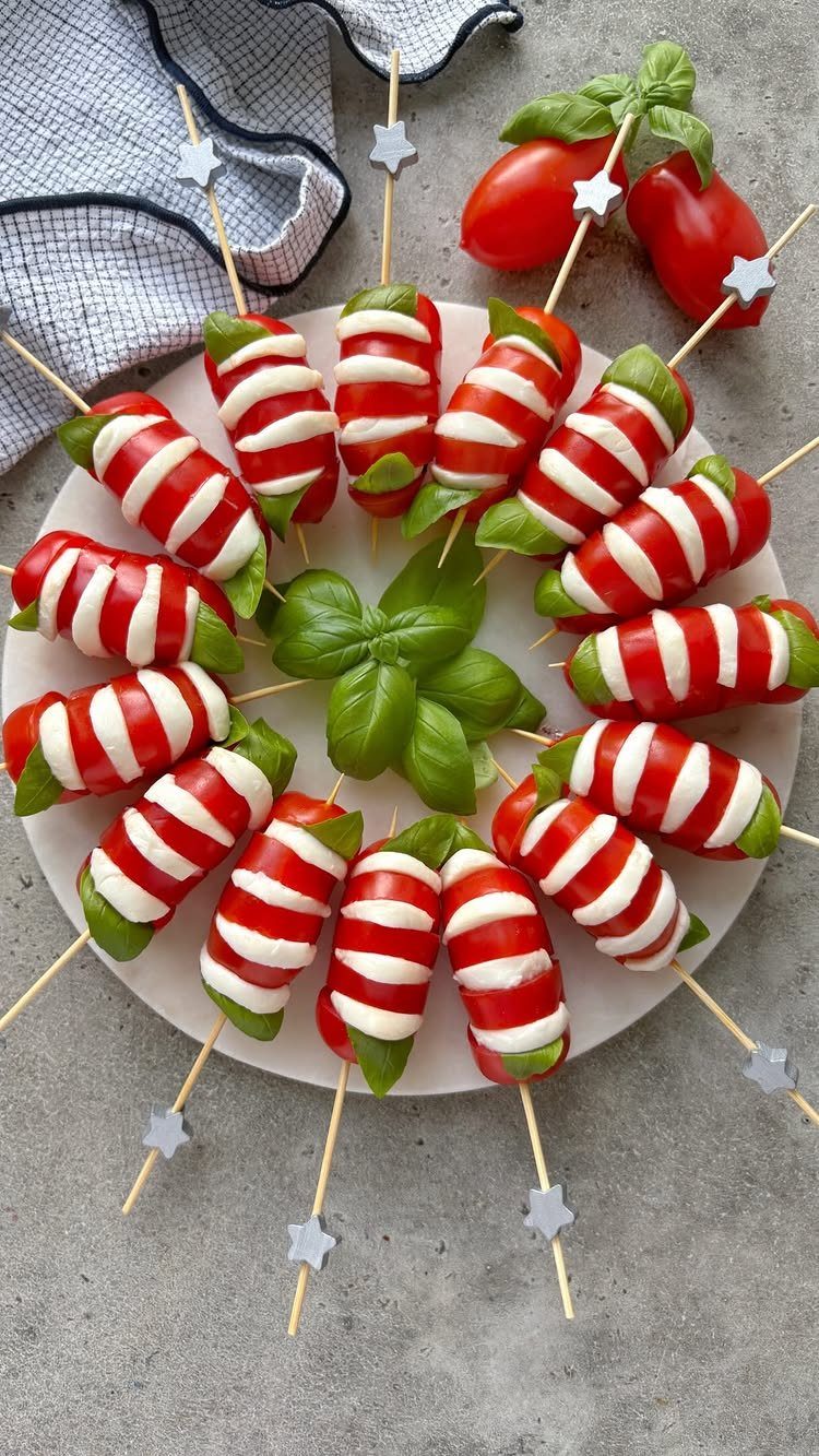 Caprese skewers with cherry tomatoes, mozzarella, and basil on a white plate.