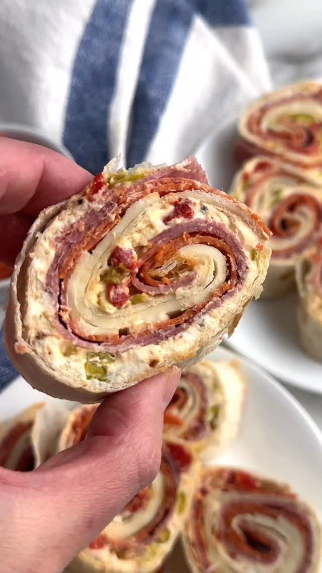 Tortilla pinwheels filled with cream cheese and salami held by a hand.