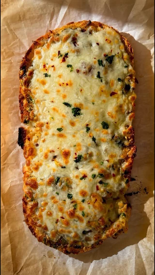 Cheesy garlic flatbread with melted white cheese and herbs on parchment paper