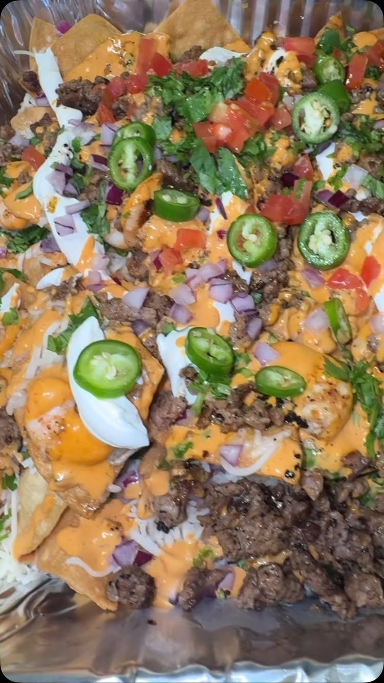 Loaded nachos with melted cheese, ground beef, jalapeños, and sour cream in foil.