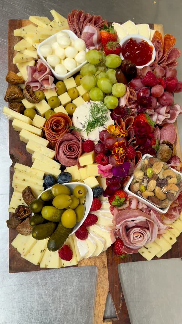 Charcuterie board with assorted cheeses, cured meats, fresh fruits, olives, and nuts.