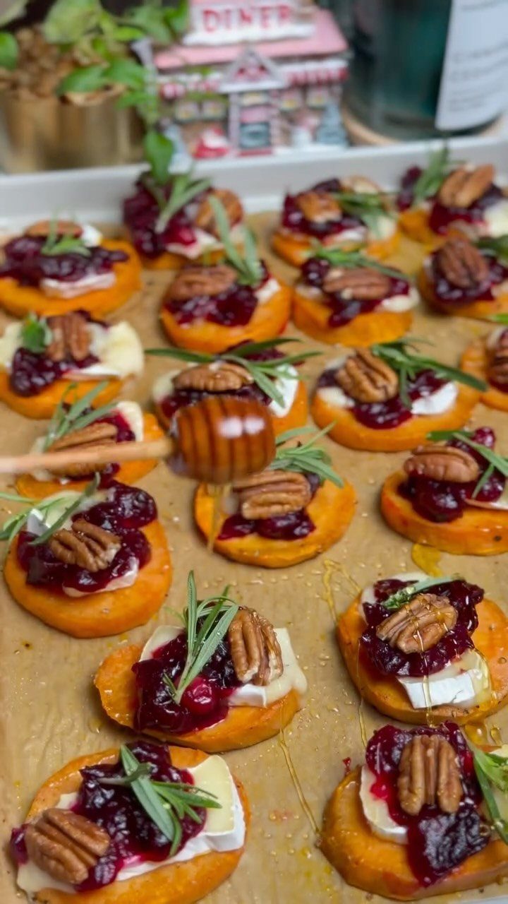 Sweet potato rounds topped with brie, cranberry jam, pecans, and rosemary with honey drizzle