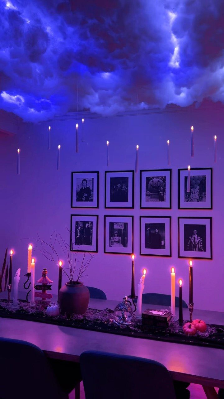 Halloween table setting with purple lighting, floating candles, and a cloud ceiling.