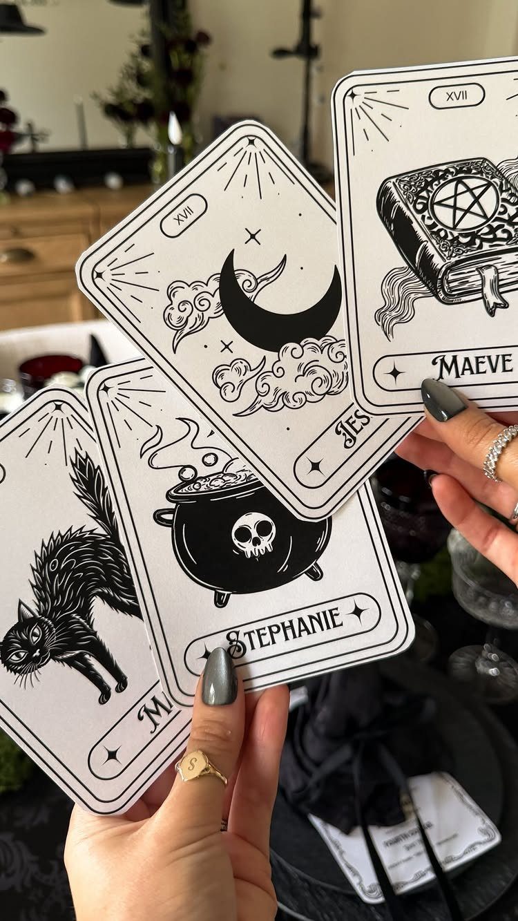 Tarot-style place cards with Halloween illustrations held over a dark table setting.