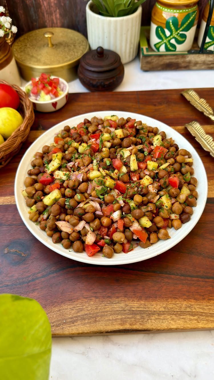Chickpea salad with diced red peppers and herbs on a white plate.