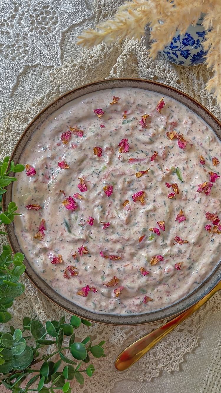 Creamy pink yogurt dip topped with dried rose petals in a ceramic bowl.