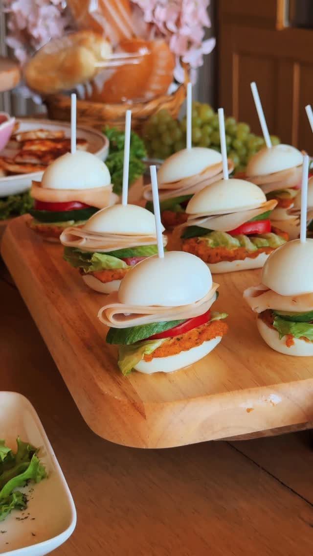 Mini sliders using hard-boiled egg whites as buns on a wooden board.