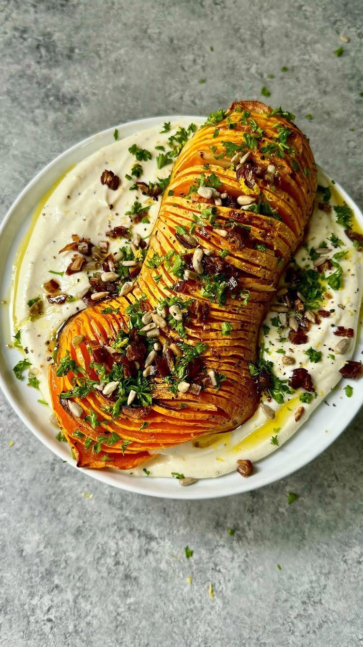Roasted sliced butternut squash on a bed of creamy white dip with herbs