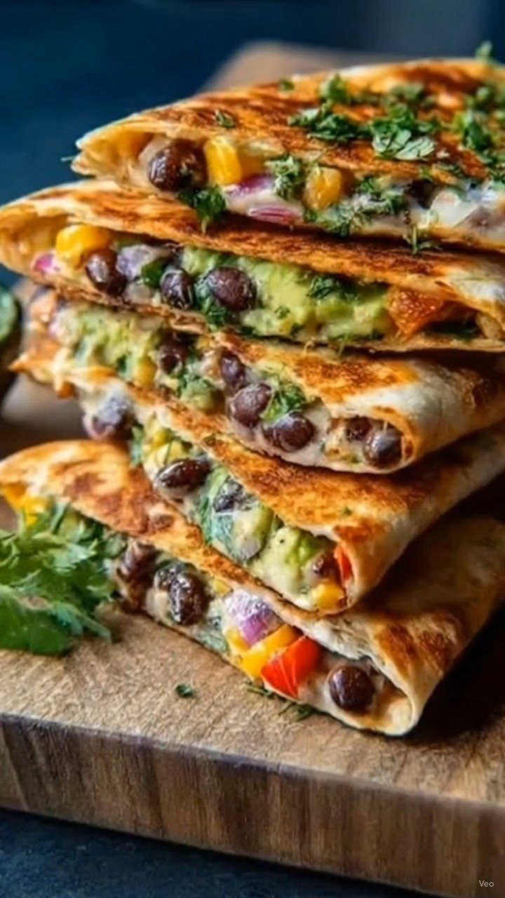Stacked toasted quesadillas filled with black beans, corn, and cheese on wooden board.