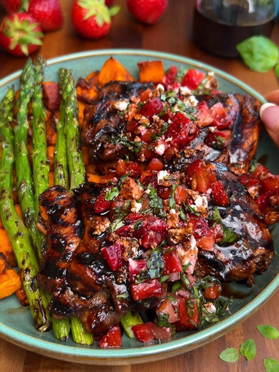 Glazed chicken breasts with tomato salsa, grilled asparagus, and roasted sweet potatoes on a plate.