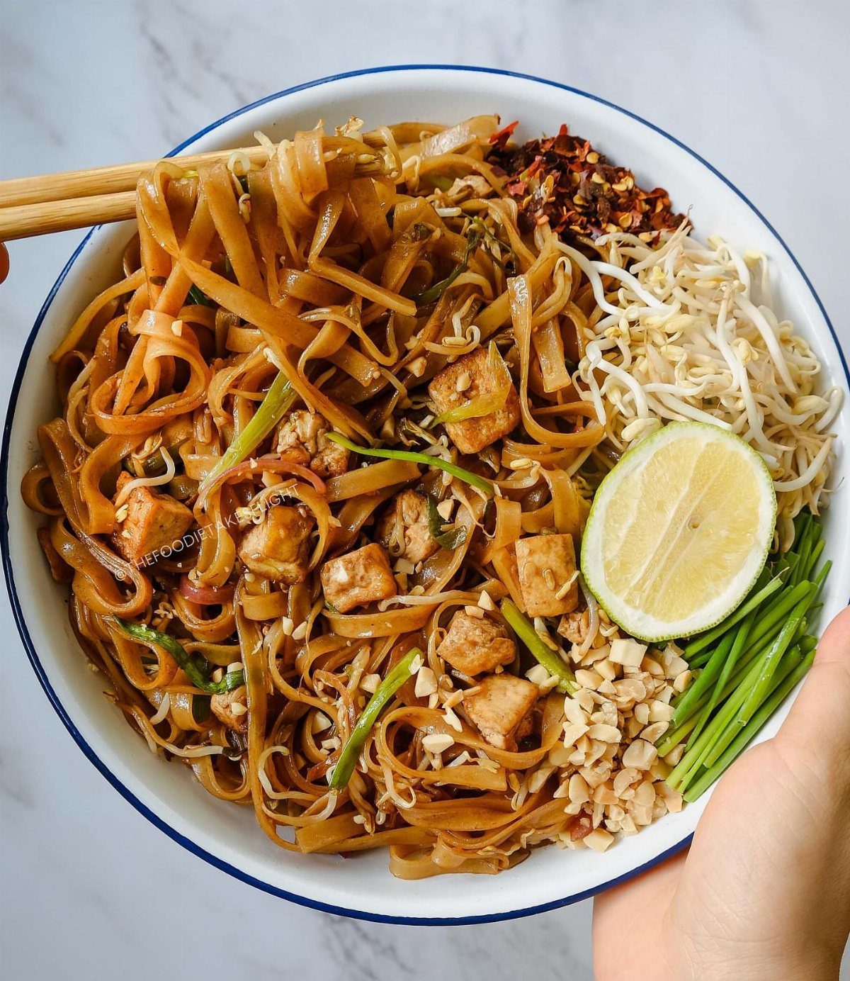 Pad Thai noodles with tofu, bean sprouts, and lime in a white bowl.