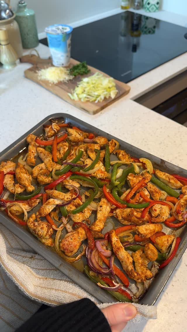 Seasoned chicken strips and colorful bell peppers roasted on a metal baking tray.