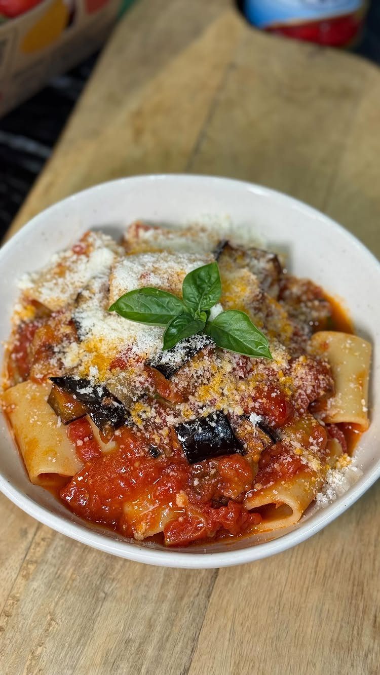 Pasta with tomato sauce, fried eggplant, and grated cheese topped with fresh basil.