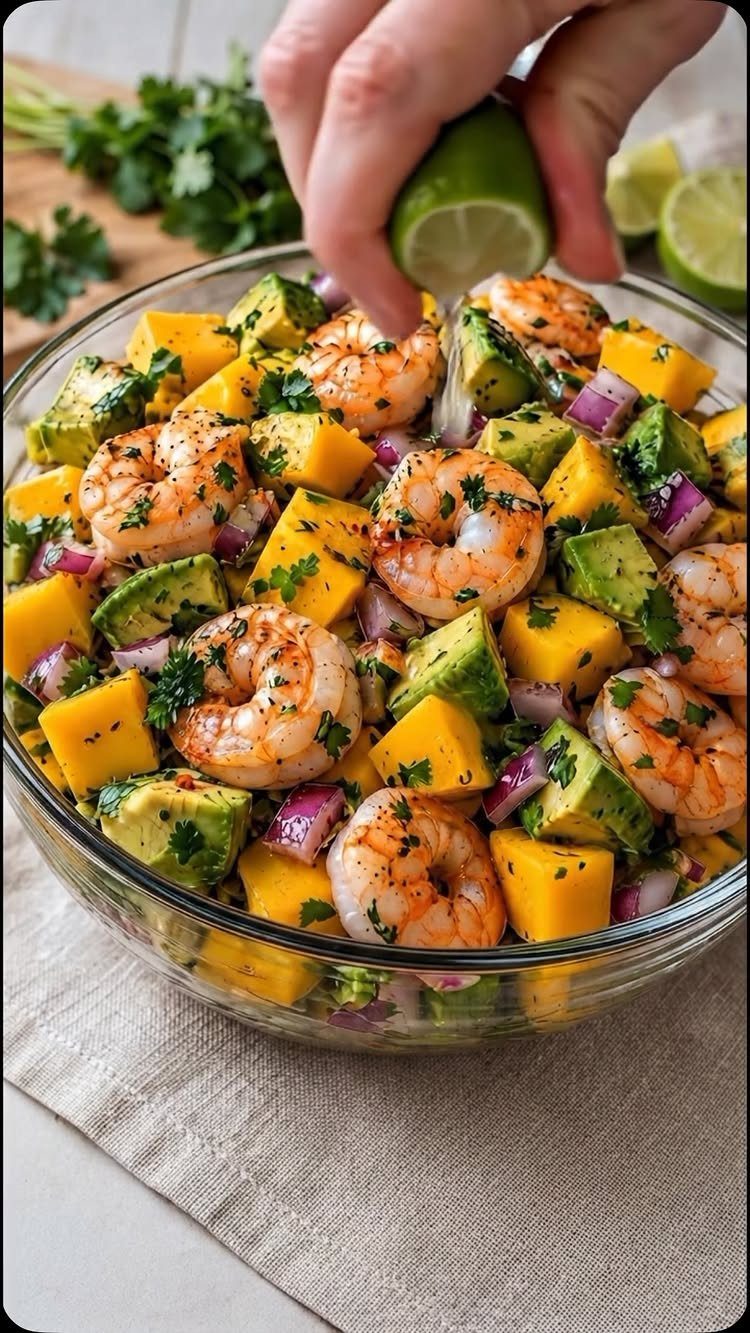 Grilled shrimp and mango salad with avocado and lime in a glass bowl
