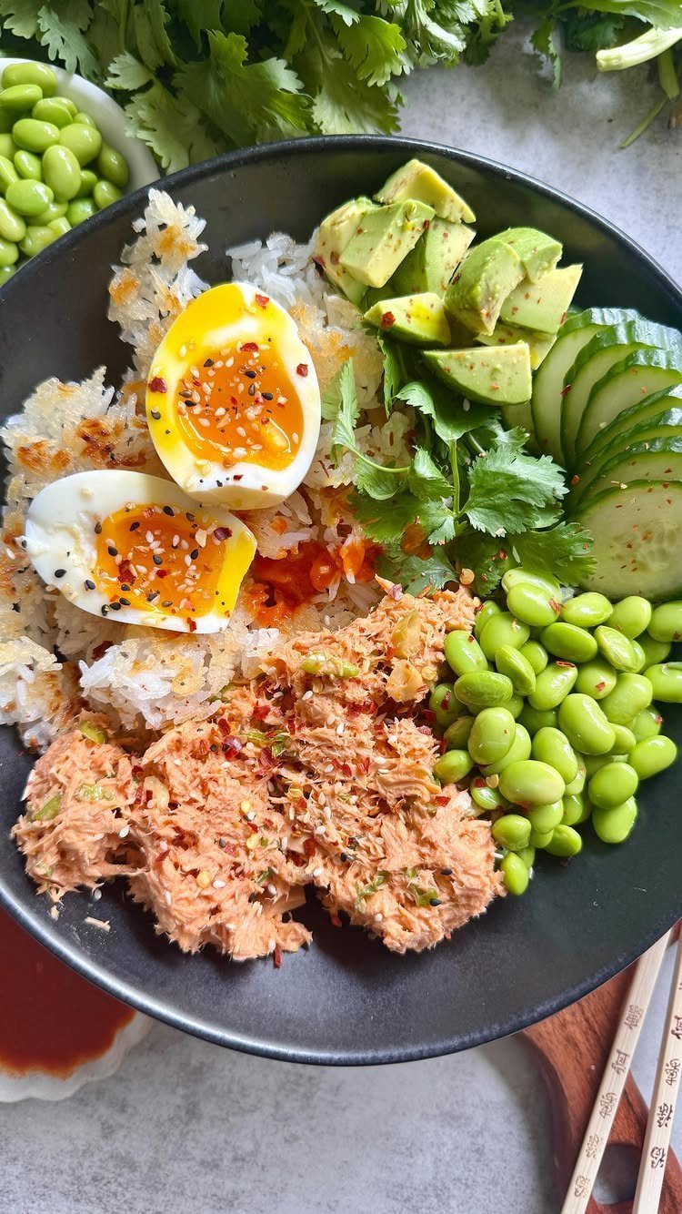 Poke bowl with spicy tuna, soft-boiled egg, avocado, edamame, and white rice.