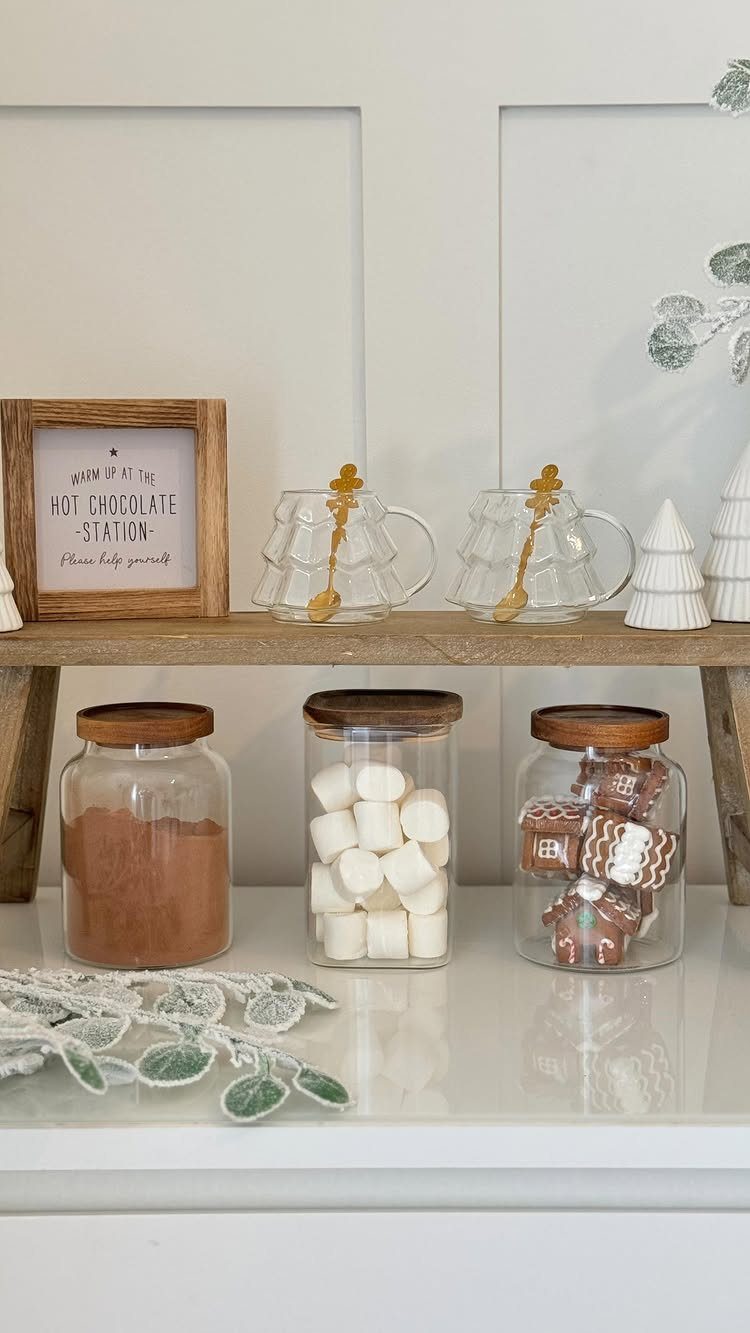 Hot chocolate station with cocoa powder, marshmallows, and chocolates in glass jars.