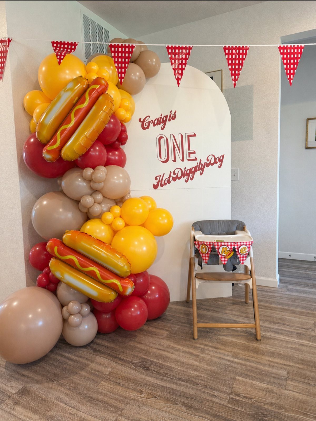 Hot dog themed birthday backdrop with balloon arch and custom signage for a child.