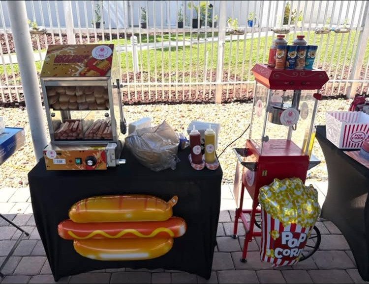 Hot dog steamer and popcorn machine setup with a large hot dog inflatable decoration.