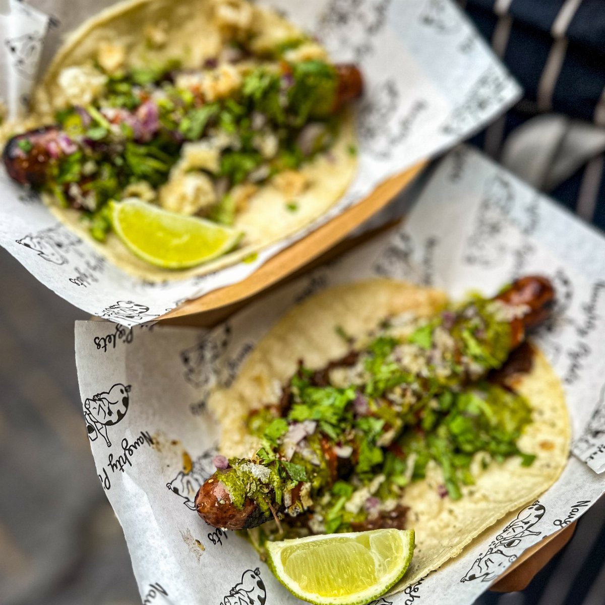 Street corn taco dogs with cilantro and lime in paper lined trays