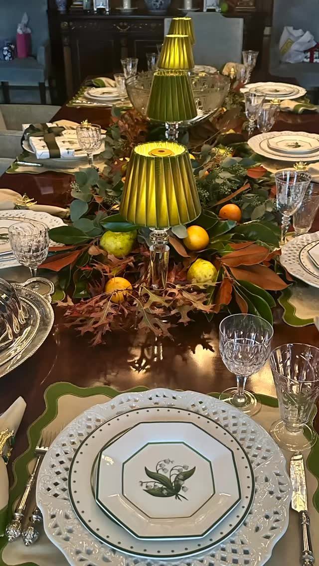Formal table setting with white plates, crystal glasses, and autumn leaf centerpieces.