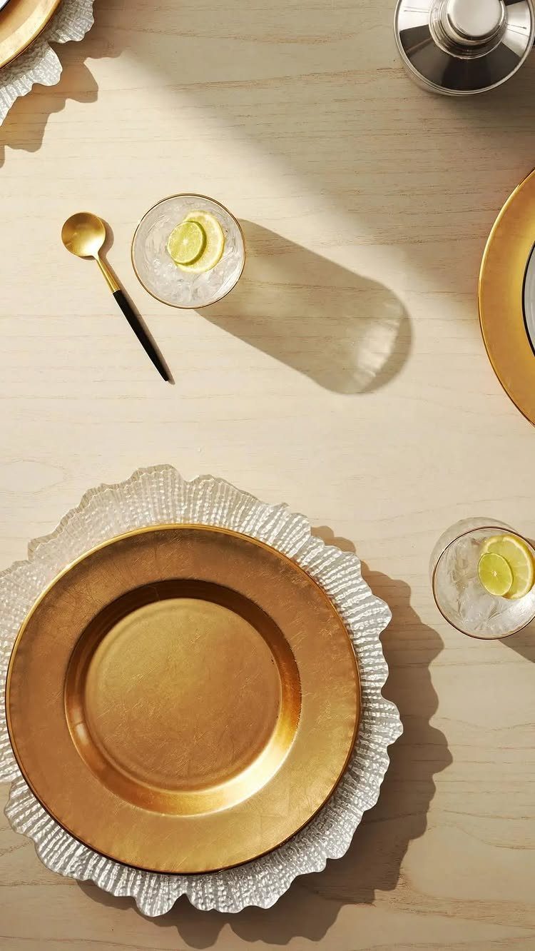 Gold dinner plates resting on a white textured charger plate on a wooden table.