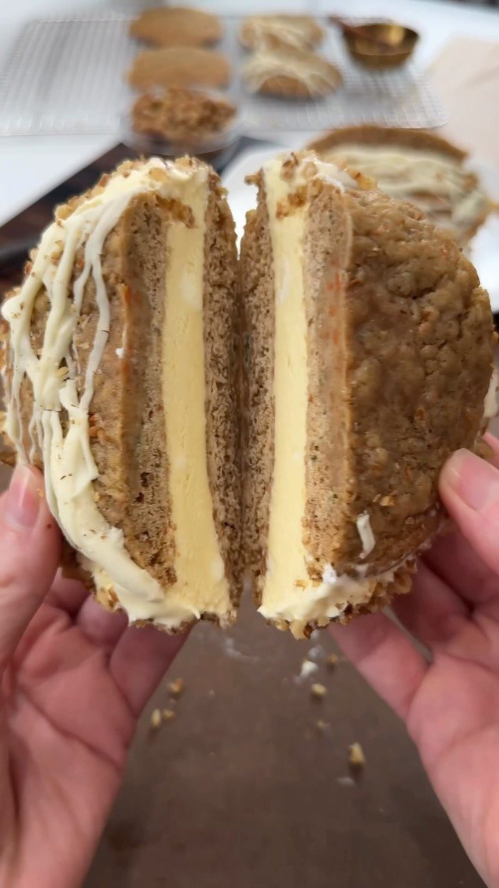 Ice cream sandwich split in half showing yellow filling and textured brown cookies.