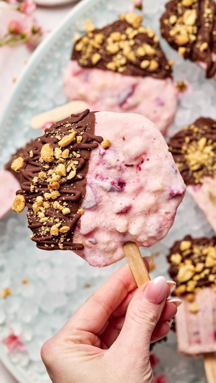 Strawberry ice cream pops dipped in chocolate and nuts on an icy platter