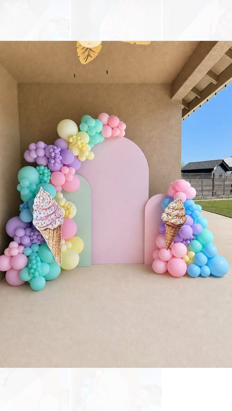Pastel arched backdrop with balloon garlands and large ice cream cone cutouts.