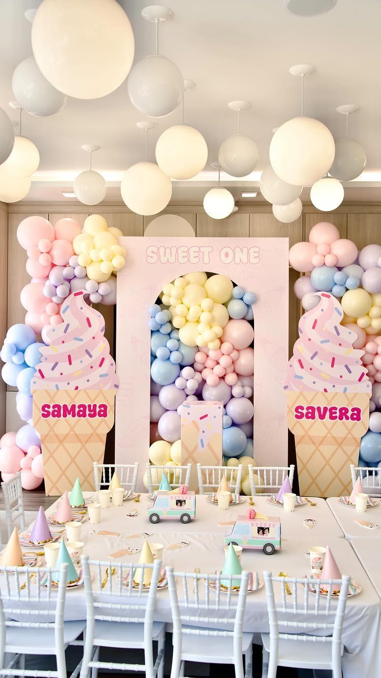 Pastel balloon arches and large ice cream cone cutouts decorating a party table.