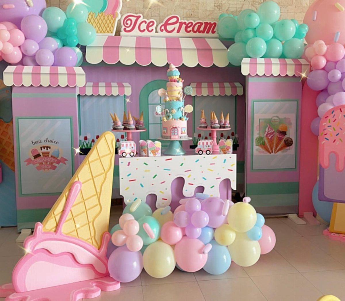 Pastel ice cream party setup with balloons, themed booth, and large cone cutout.