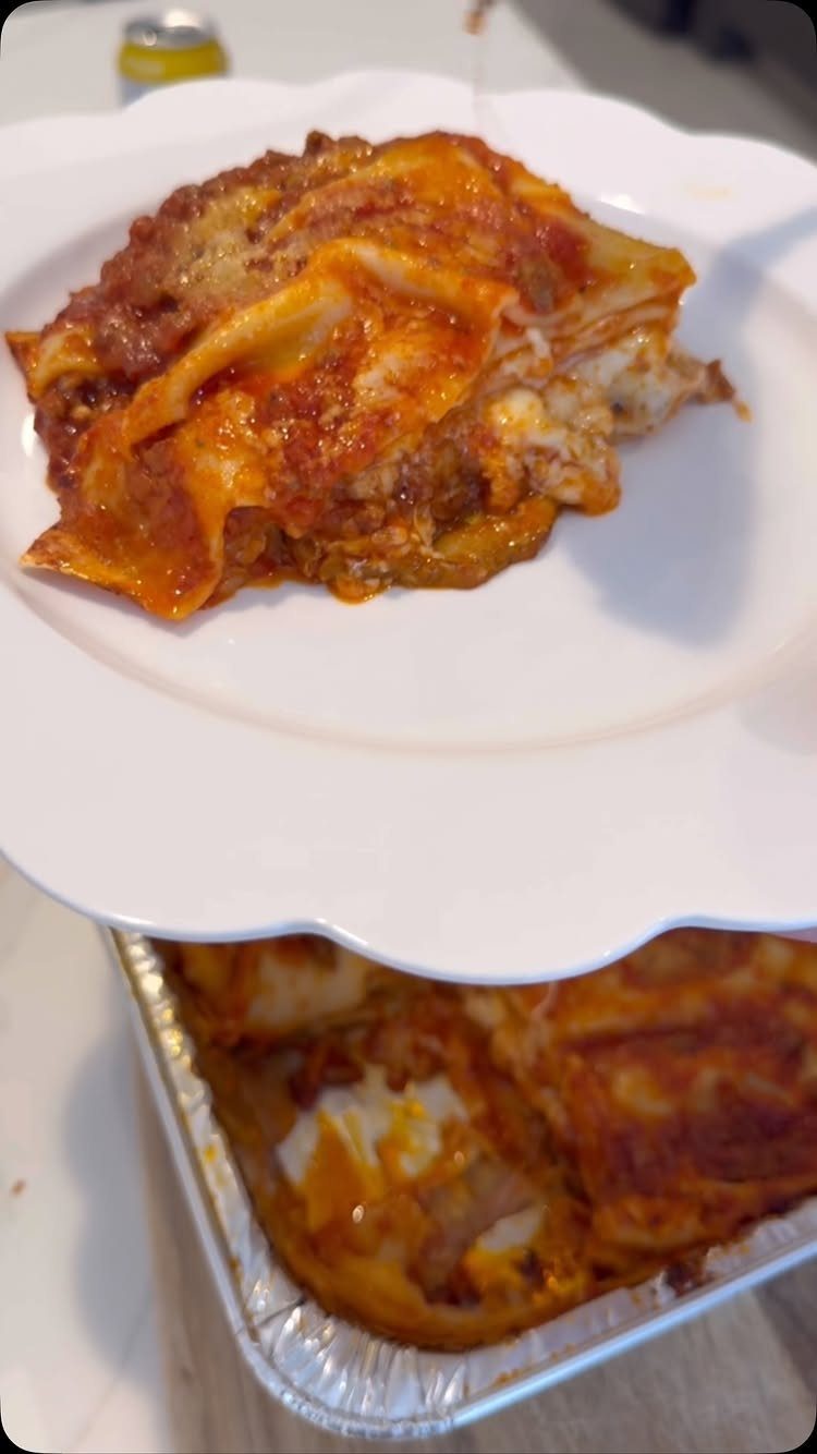 Lasagna slice with meat sauce and cheese on a white plate.