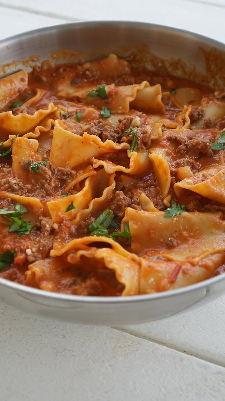 Lasagne soup with wavy noodles and ground meat in a silver pot.