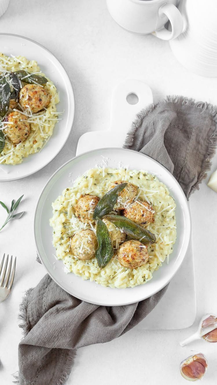 Creamy yellow risotto topped with fried balls and sage leaves on white plates.