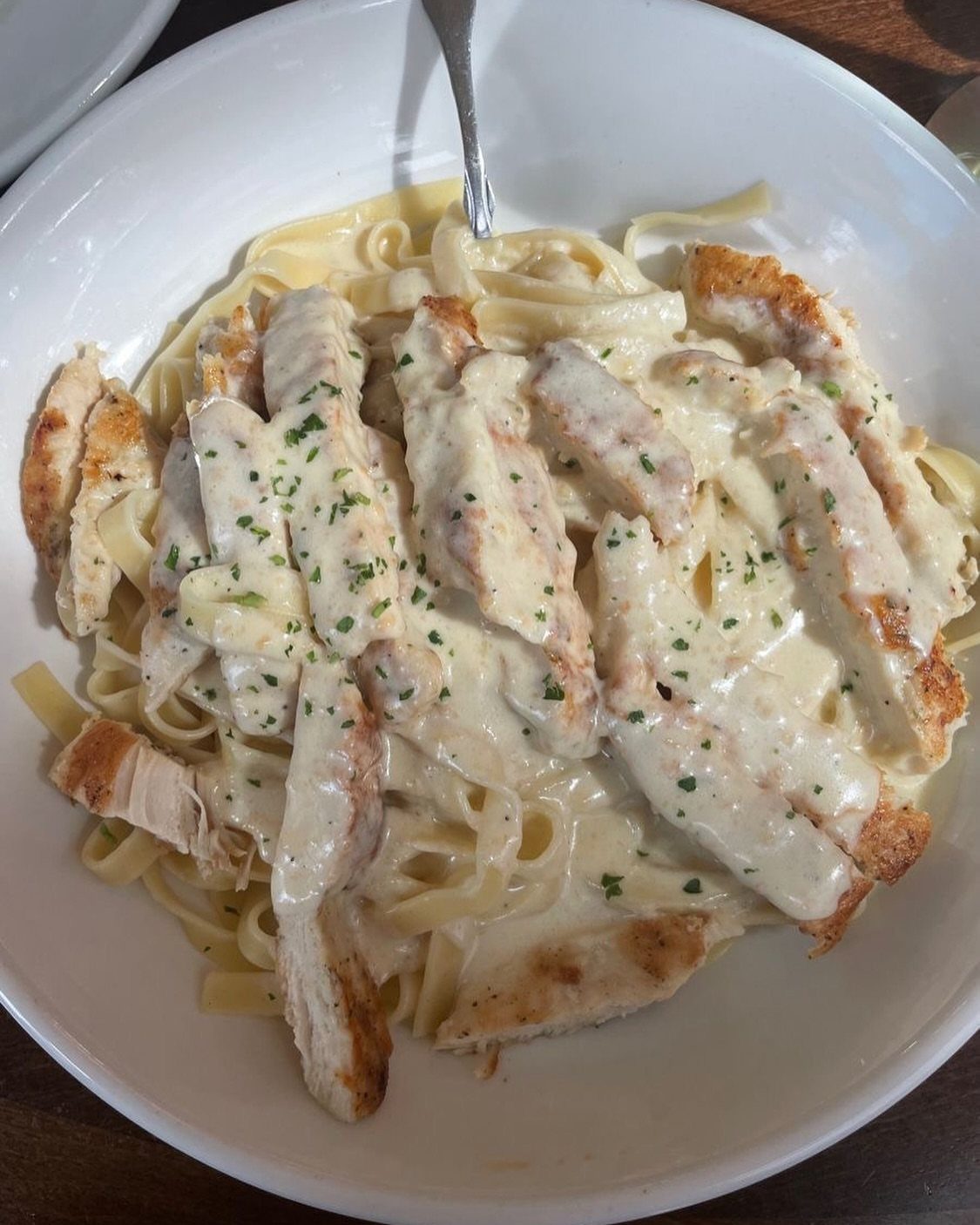 Fettuccine pasta with grilled chicken in a creamy white sauce in a bowl