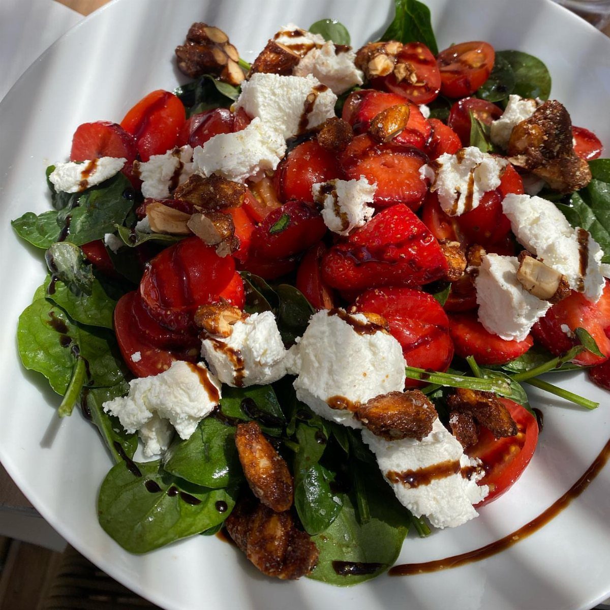 Strawberry arugula salad with feta cheese, glazed walnuts, and balsamic glaze in a bowl