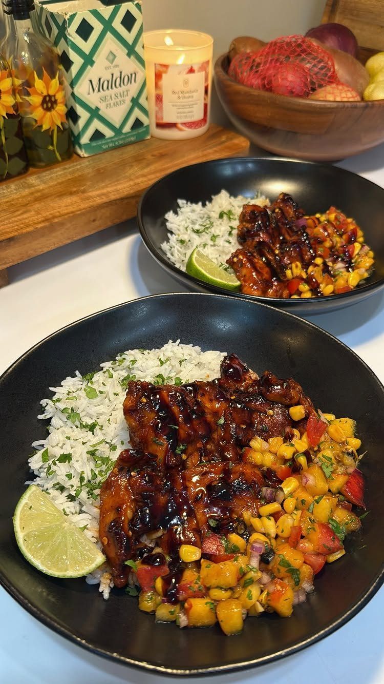 Glazed grilled chicken thighs served with white rice and mango corn salsa in bowls.