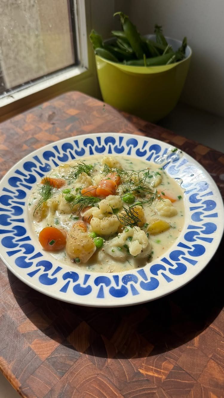Creamy vegetable soup with carrots and cauliflower in a blue patterned bowl.