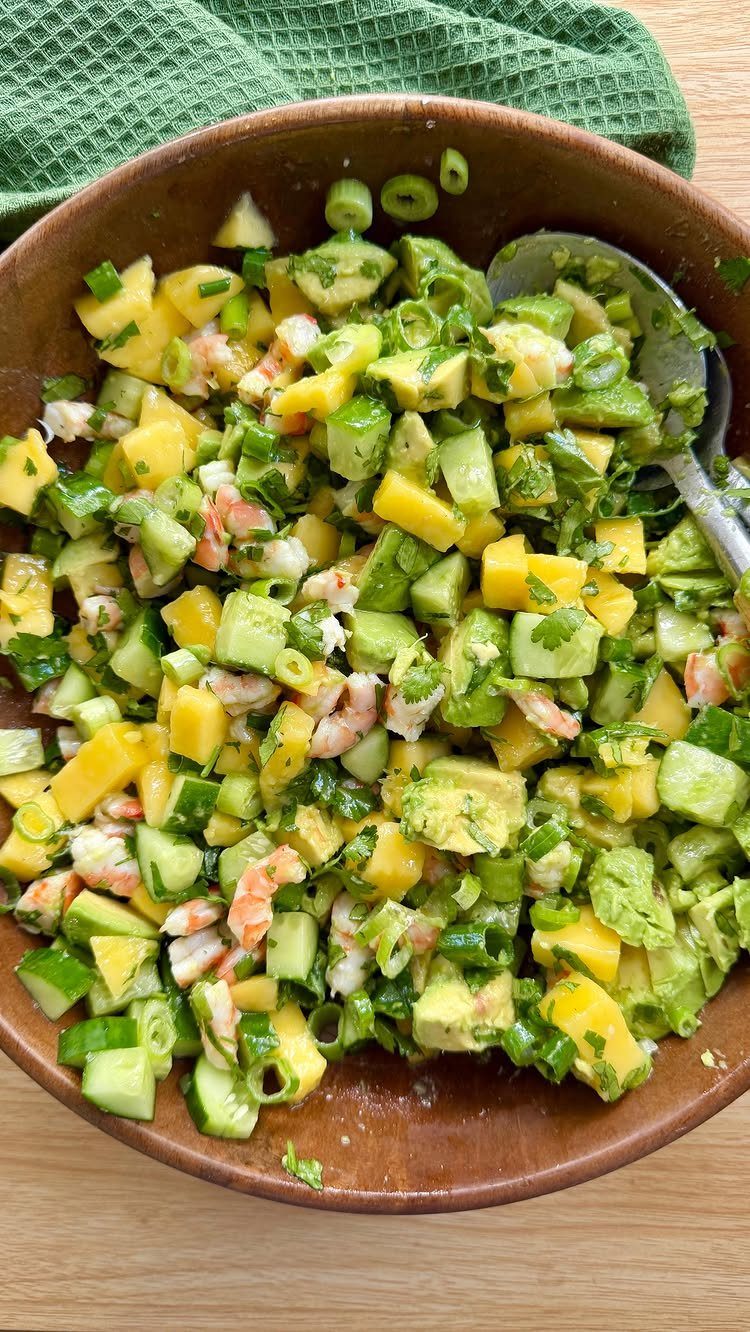 Thai prawn mango salad with cucumber and avocado in a wooden bowl