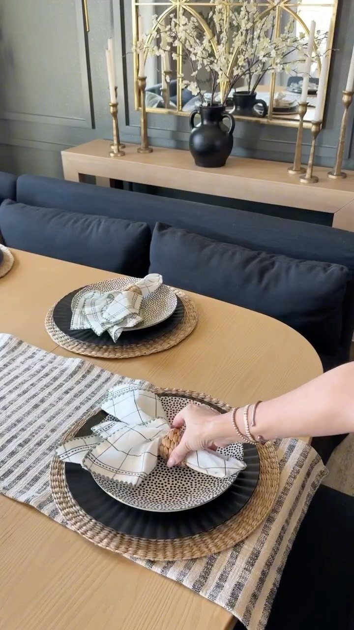 Modern dining table setting with patterned plates, woven placemats, and a striped runner.