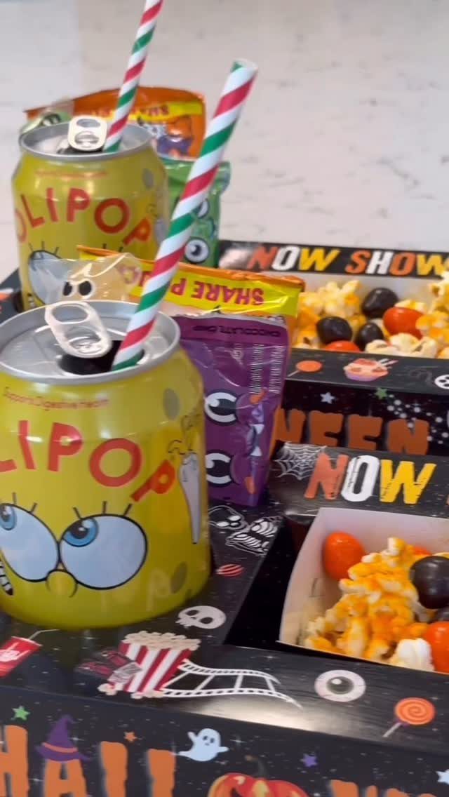 Halloween themed movie snack box with yellow drinks, popcorn, and assorted candies.